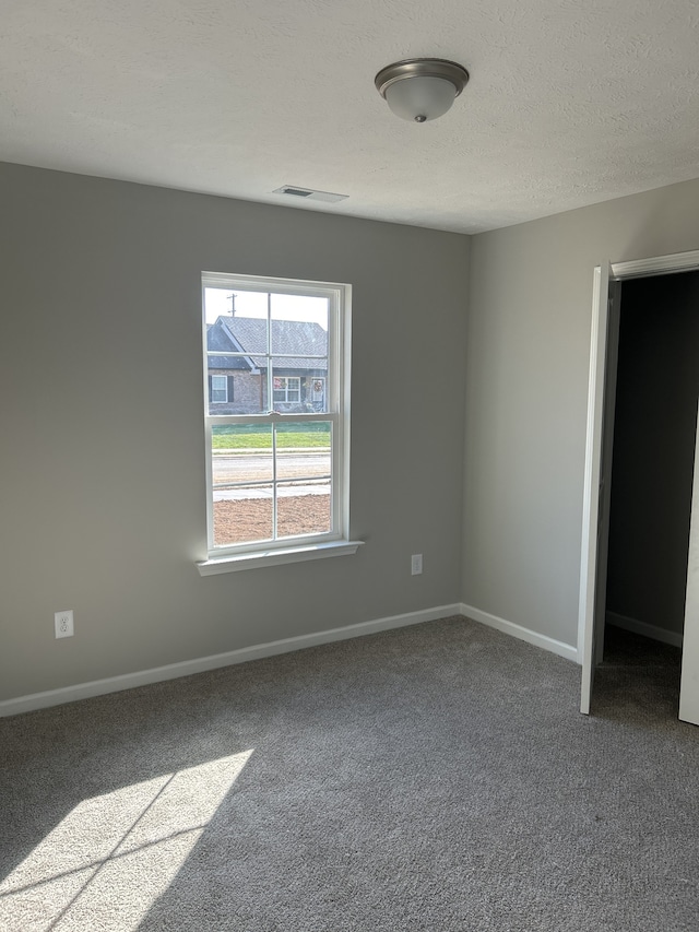 unfurnished bedroom with carpet floors, a textured ceiling, and baseboards