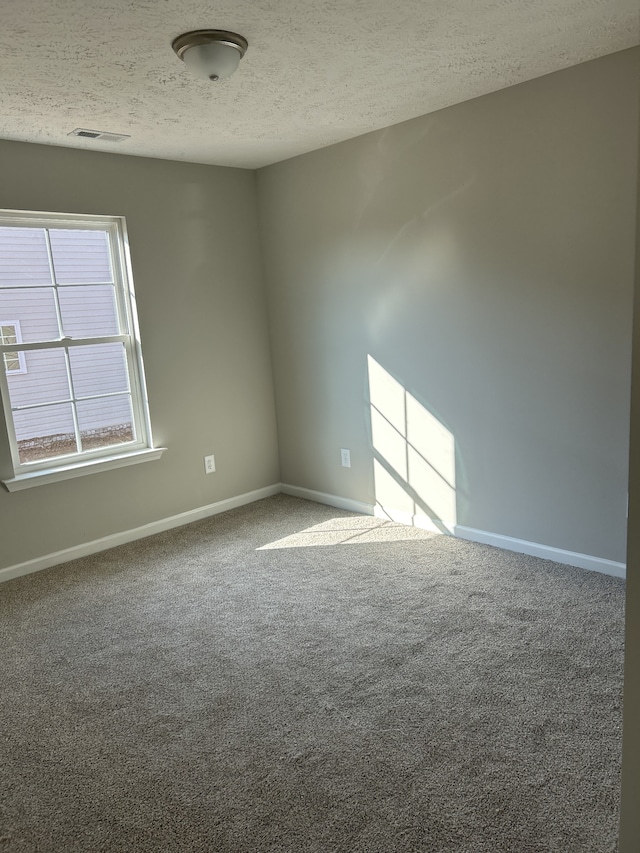 carpeted spare room featuring baseboards and a textured ceiling