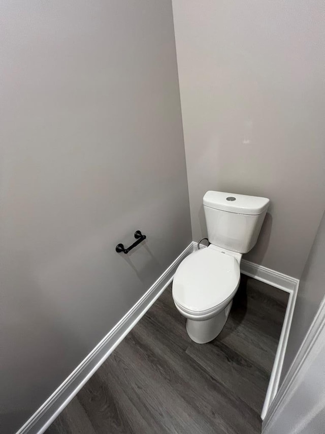 bathroom with toilet, wood finished floors, and baseboards