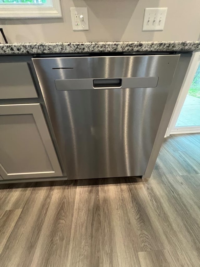 room details with dishwasher, dark stone counters, and dark wood-type flooring