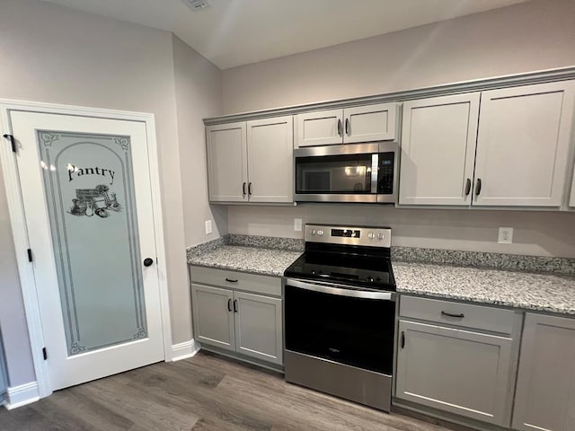 kitchen featuring gray cabinetry, dark wood-style floors, baseboards, and stainless steel appliances