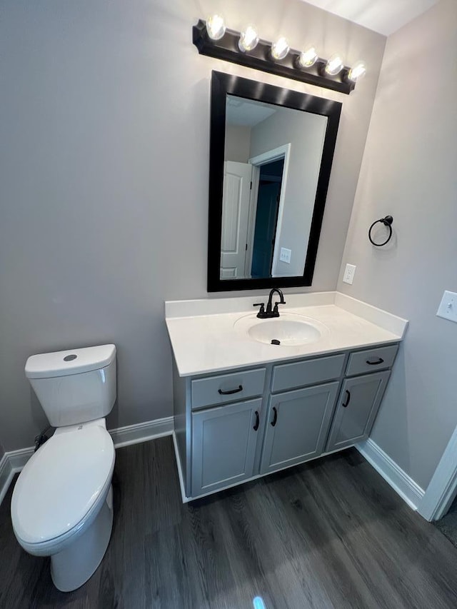 bathroom with toilet, wood finished floors, and baseboards