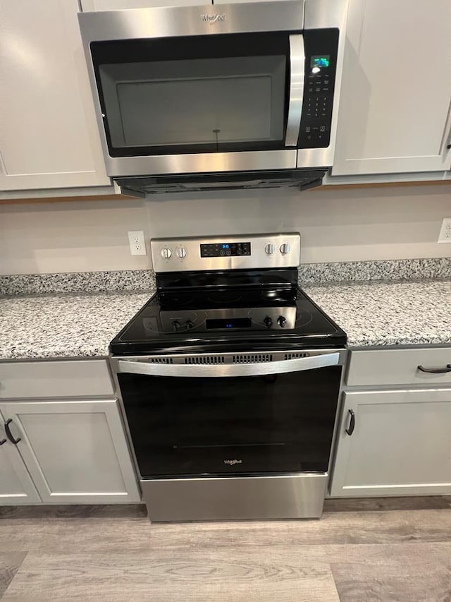 kitchen featuring light wood-style flooring, light stone countertops, and stainless steel appliances