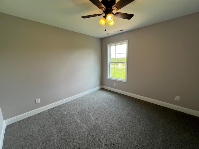 unfurnished room featuring baseboards, visible vents, dark carpet, and ceiling fan