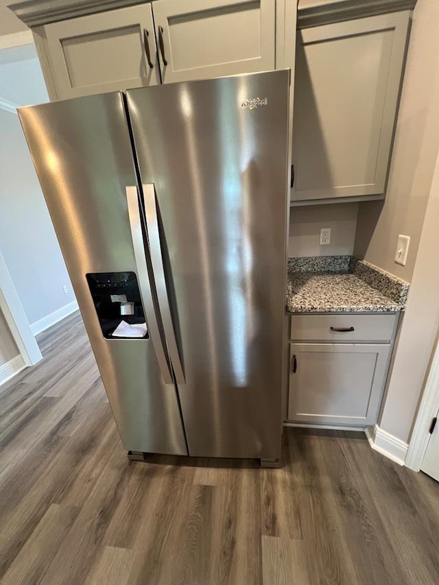 details with light stone counters, dark wood-style floors, and stainless steel fridge