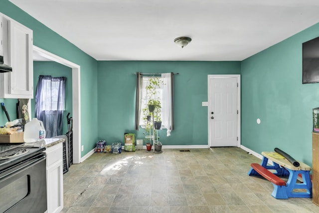 kitchen with white cabinets, light tile patterned flooring, and range with electric stovetop