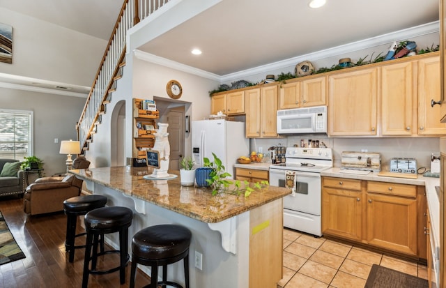 kitchen featuring crown molding, a kitchen breakfast bar, light wood-type flooring, white appliances, and a kitchen island