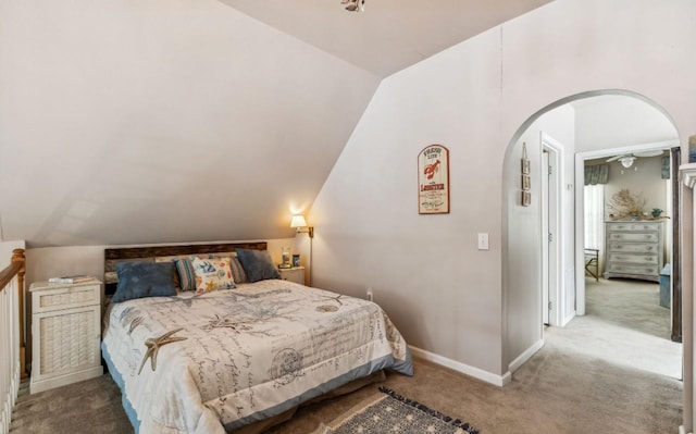 bedroom featuring baseboards, arched walkways, vaulted ceiling, and carpet flooring