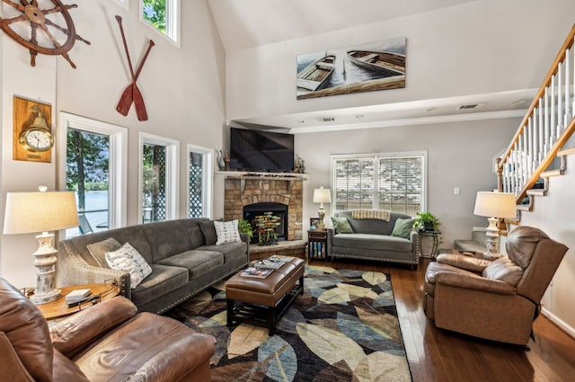 living room with a fireplace, a high ceiling, dark hardwood / wood-style flooring, and a healthy amount of sunlight