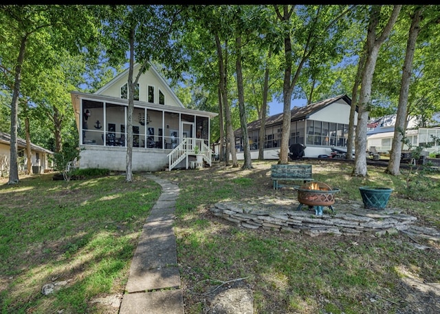 rear view of property with a sunroom and a fire pit