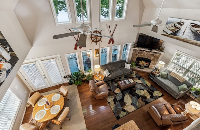 living room with high vaulted ceiling, a stone fireplace, dark hardwood / wood-style floors, and ceiling fan