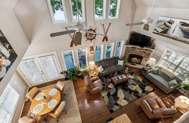 living room featuring ceiling fan, high vaulted ceiling, a fireplace, and wood finished floors