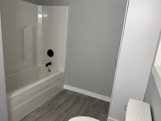 bathroom with bathing tub / shower combination, toilet, and hardwood / wood-style floors