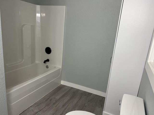 bathroom with hardwood / wood-style flooring,  shower combination, and toilet