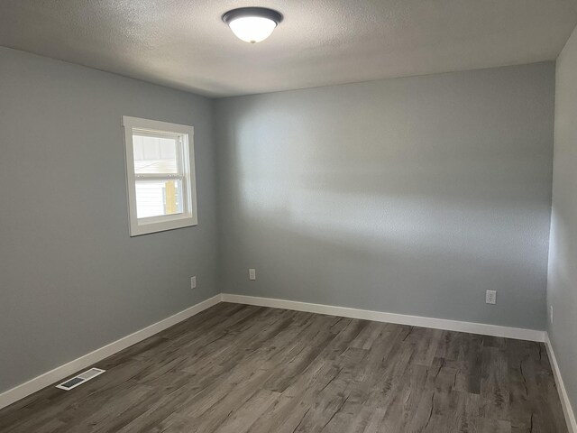 empty room featuring a textured ceiling and dark hardwood / wood-style flooring