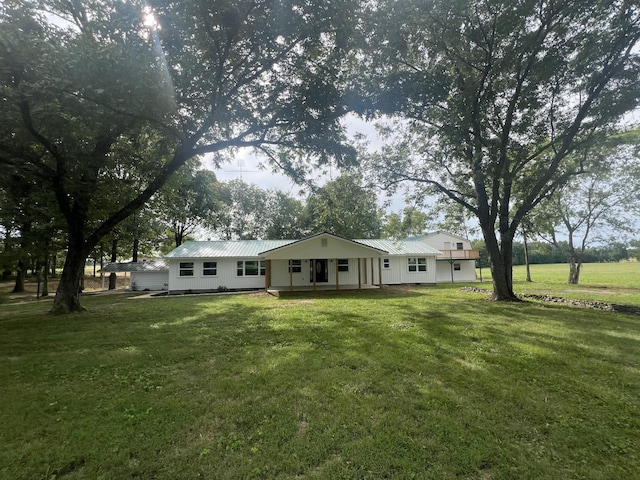 rear view of property featuring covered porch and a lawn