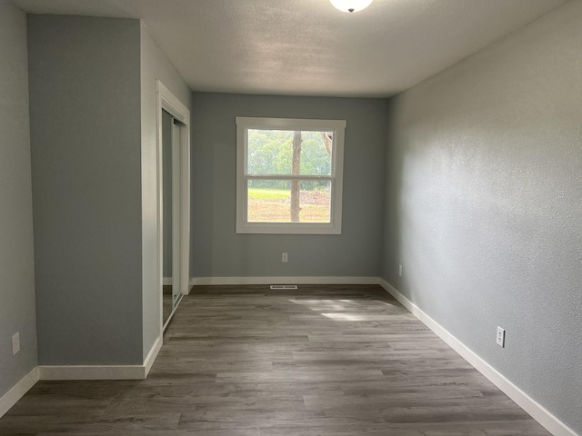 unfurnished room with wood-type flooring and a textured ceiling