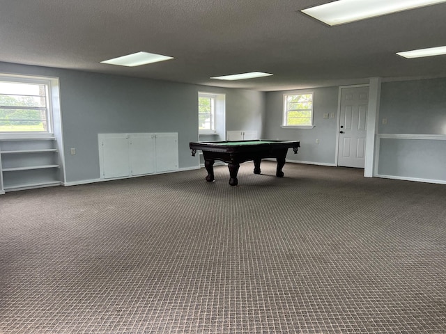 recreation room with a wealth of natural light, a textured ceiling, and dark colored carpet