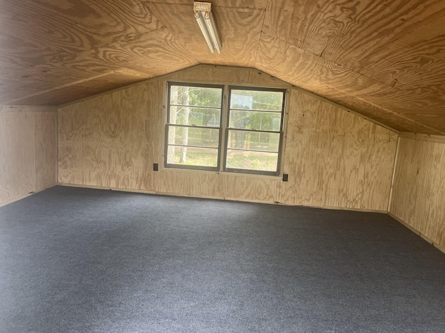 additional living space featuring dark colored carpet, wood walls, lofted ceiling, and wooden ceiling