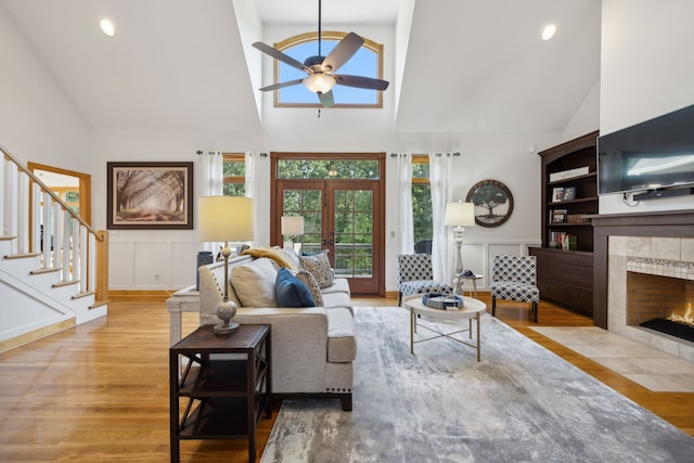 living room with a tile fireplace, high vaulted ceiling, light hardwood / wood-style flooring, and ceiling fan