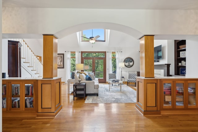 living room with ceiling fan, light wood-type flooring, french doors, and decorative columns