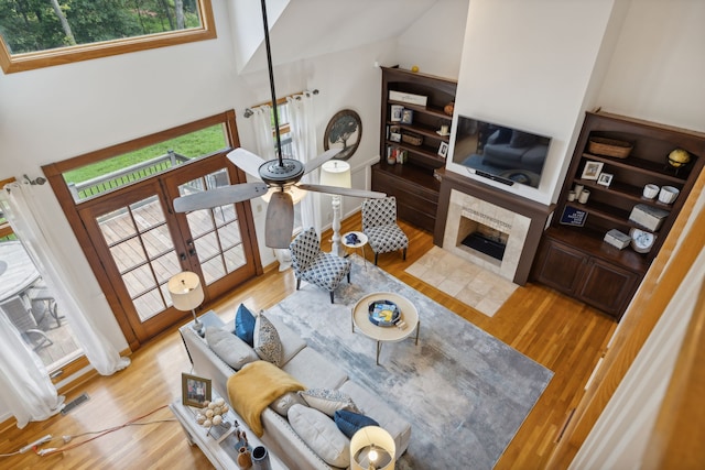 living room with a fireplace, a high ceiling, and light hardwood / wood-style floors