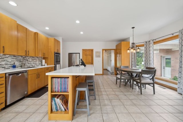 kitchen with tasteful backsplash, appliances with stainless steel finishes, a chandelier, a center island, and decorative light fixtures