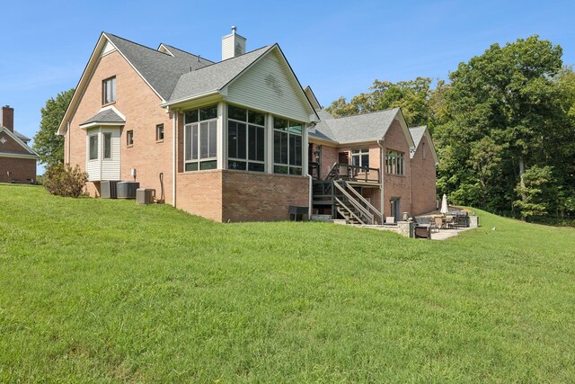 back of house featuring central air condition unit, a lawn, a sunroom, and a patio