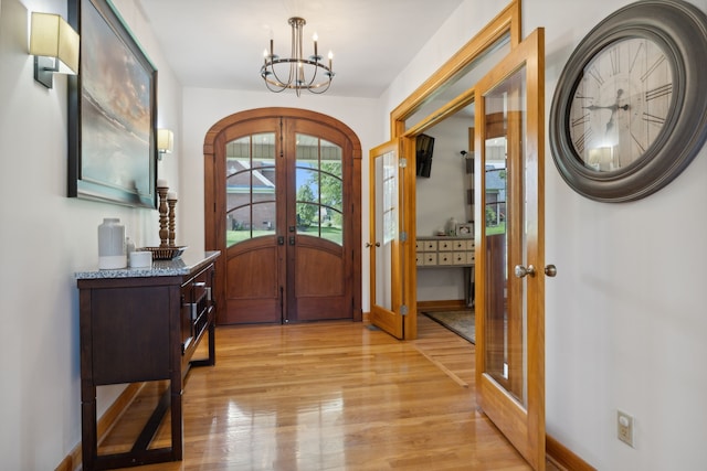 entryway with light wood-type flooring, french doors, and an inviting chandelier