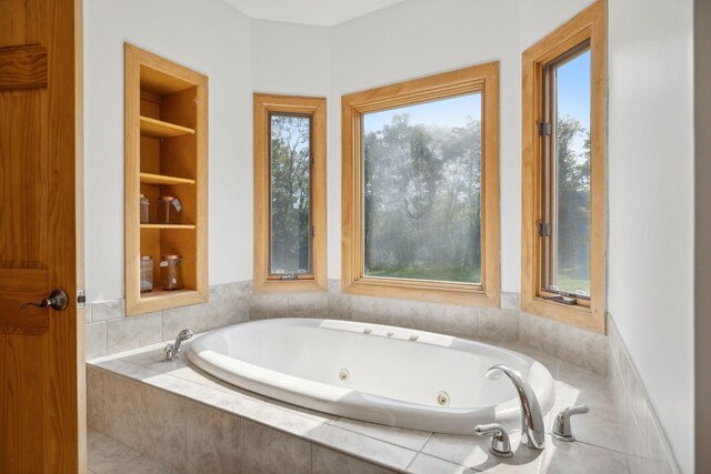 bathroom with built in shelves, tile patterned floors, and tiled tub