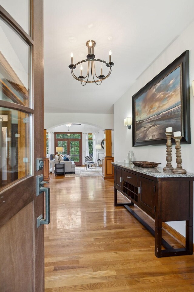 hallway with light hardwood / wood-style flooring and an inviting chandelier