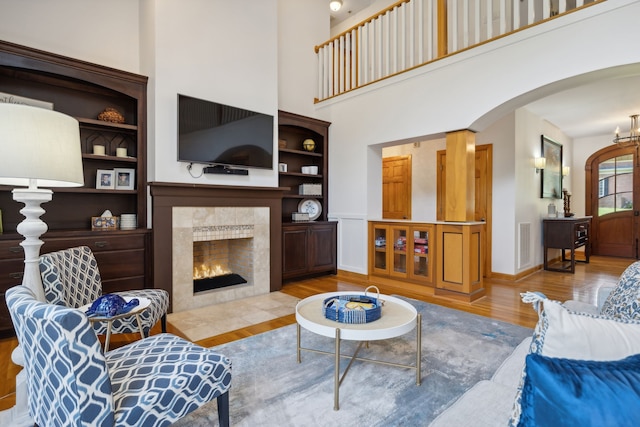 living room featuring a towering ceiling, light hardwood / wood-style flooring, and a fireplace