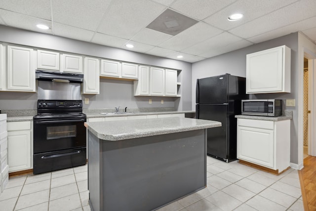 kitchen featuring black appliances, a drop ceiling, white cabinetry, and a kitchen island