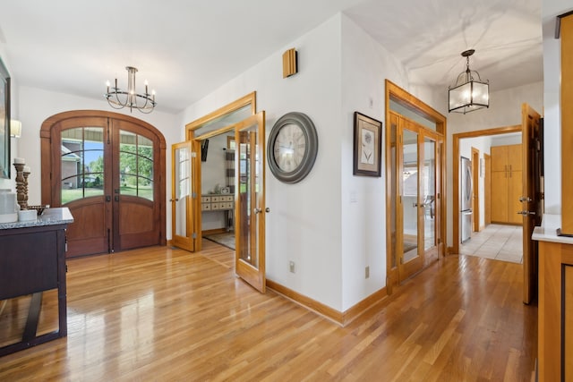 entrance foyer with french doors, an inviting chandelier, and light hardwood / wood-style floors