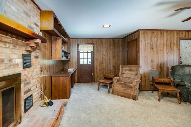 living area with ceiling fan, wood walls, carpet floors, and a brick fireplace