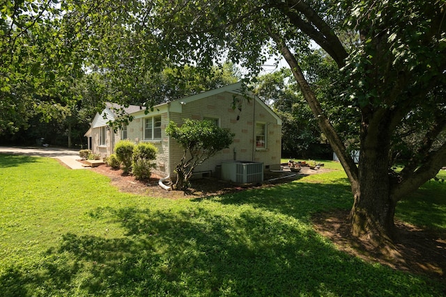 view of side of home featuring central AC unit and a yard