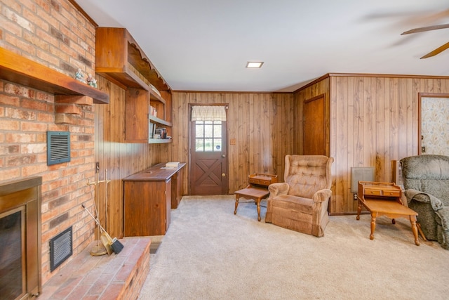 sitting room with ceiling fan, wood walls, and carpet floors