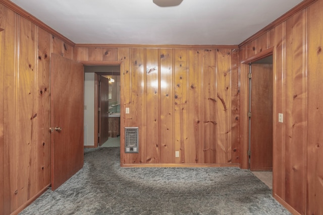 unfurnished room featuring carpet flooring, ornamental molding, heating unit, and wooden walls