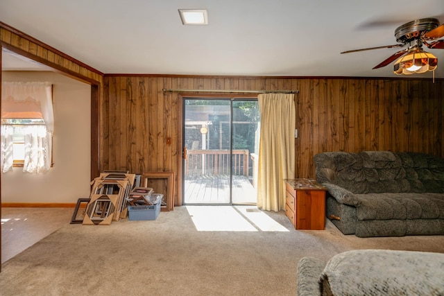 carpeted living room featuring wood walls and ceiling fan