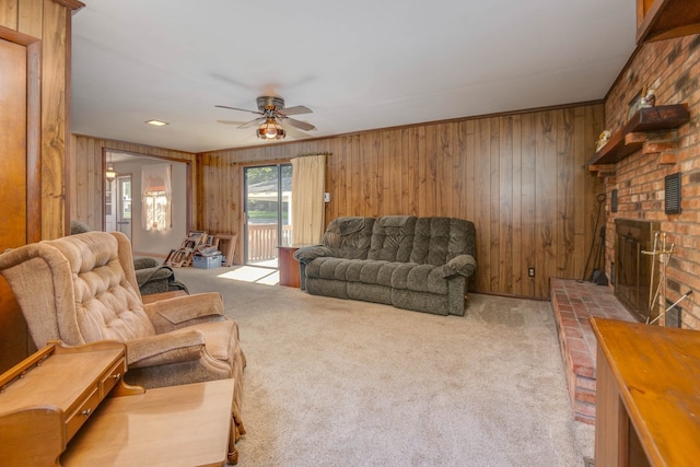 carpeted living room with a brick fireplace, brick wall, wooden walls, and ceiling fan