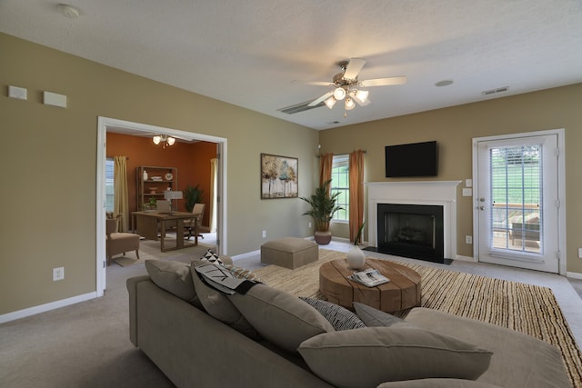 carpeted living room with ceiling fan and a textured ceiling