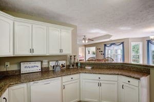 kitchen featuring dishwasher, white cabinetry, dark stone counters, ceiling fan, and kitchen peninsula