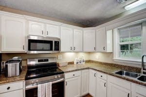 kitchen with appliances with stainless steel finishes, white cabinets, and sink