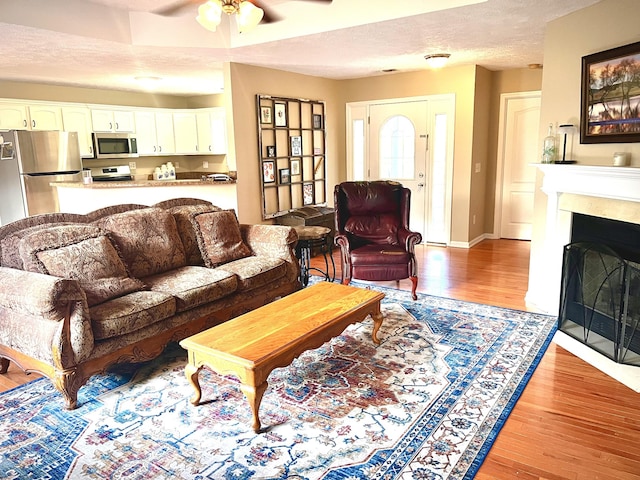 living room with ceiling fan, light hardwood / wood-style flooring, and a textured ceiling