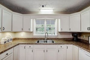 kitchen featuring dark stone counters, sink, and white cabinetry