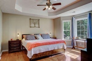 bedroom with a tray ceiling, ceiling fan, and light hardwood / wood-style floors