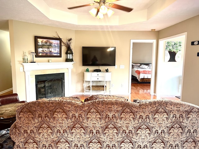 living room featuring ceiling fan, hardwood / wood-style flooring, and a raised ceiling