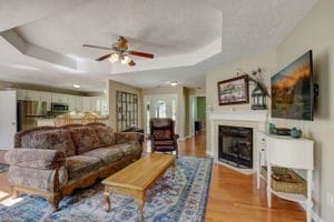 living room with ceiling fan, a tray ceiling, and light hardwood / wood-style floors