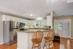 kitchen featuring kitchen peninsula, white cabinetry, stainless steel appliances, and light hardwood / wood-style floors