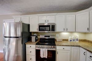 kitchen with appliances with stainless steel finishes, light stone counters, and white cabinets